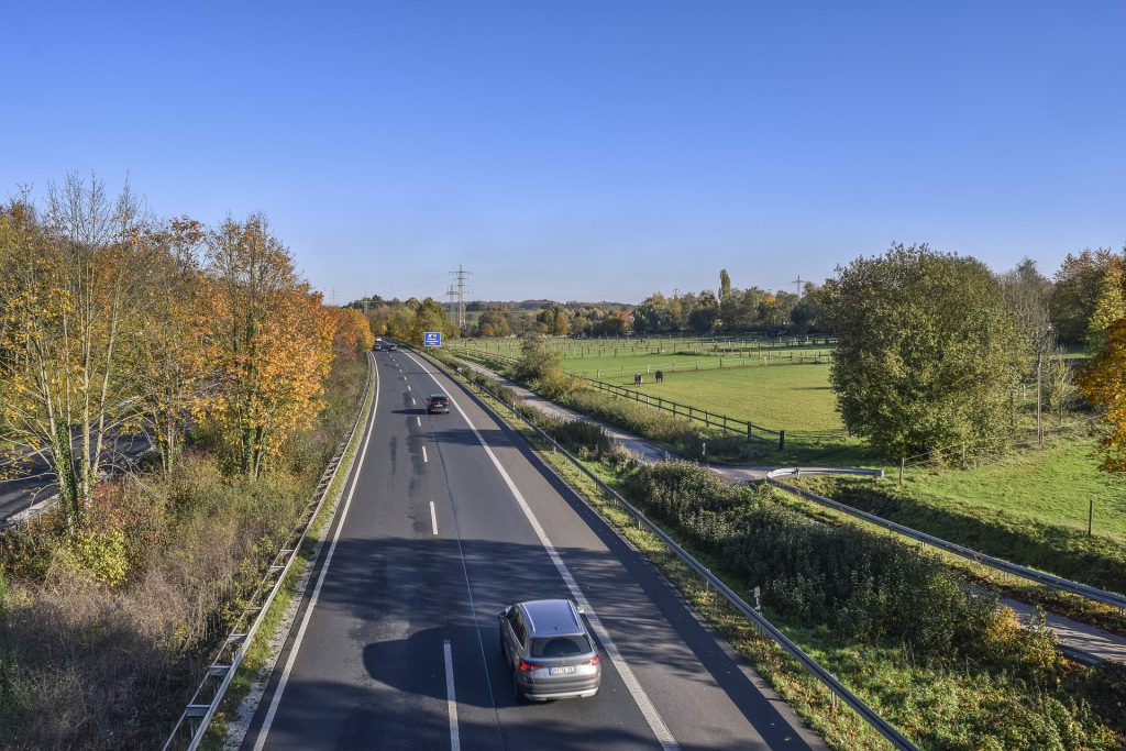 a few cars driving on a highway in Germany with plenty of green nature around