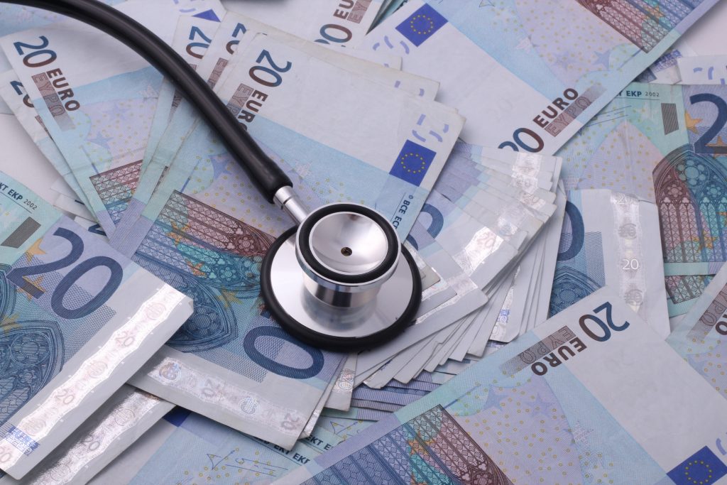 A black and silver stethoscope laying on a stash of Euro bills that reflect the amount of money doctors in Germany can earn