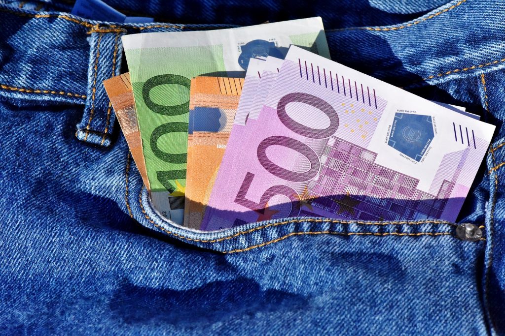 Several Euro bills appearing form a blue jean's pocket.